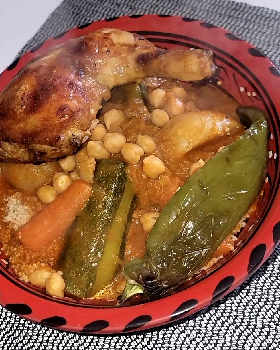 Couscous au poulet, pois chiches et légumes, dans un plat en terre rouge